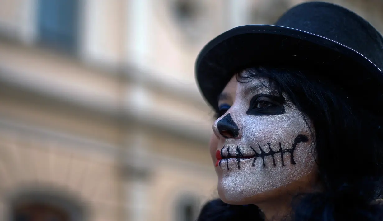 Peserta mengenakan kostum dan dandanan menyerupai zombie selama acara Zombie Walk di Sao Paulo, Brasil, Sabtu (2/11/2019). Ratusan orang turun ke jalan memakai kostum karakter horor pada acara tahunan yang digelar sejak 2006 pada Hari Para Arwah. (Miguel SCHINCARIOL / AFP)