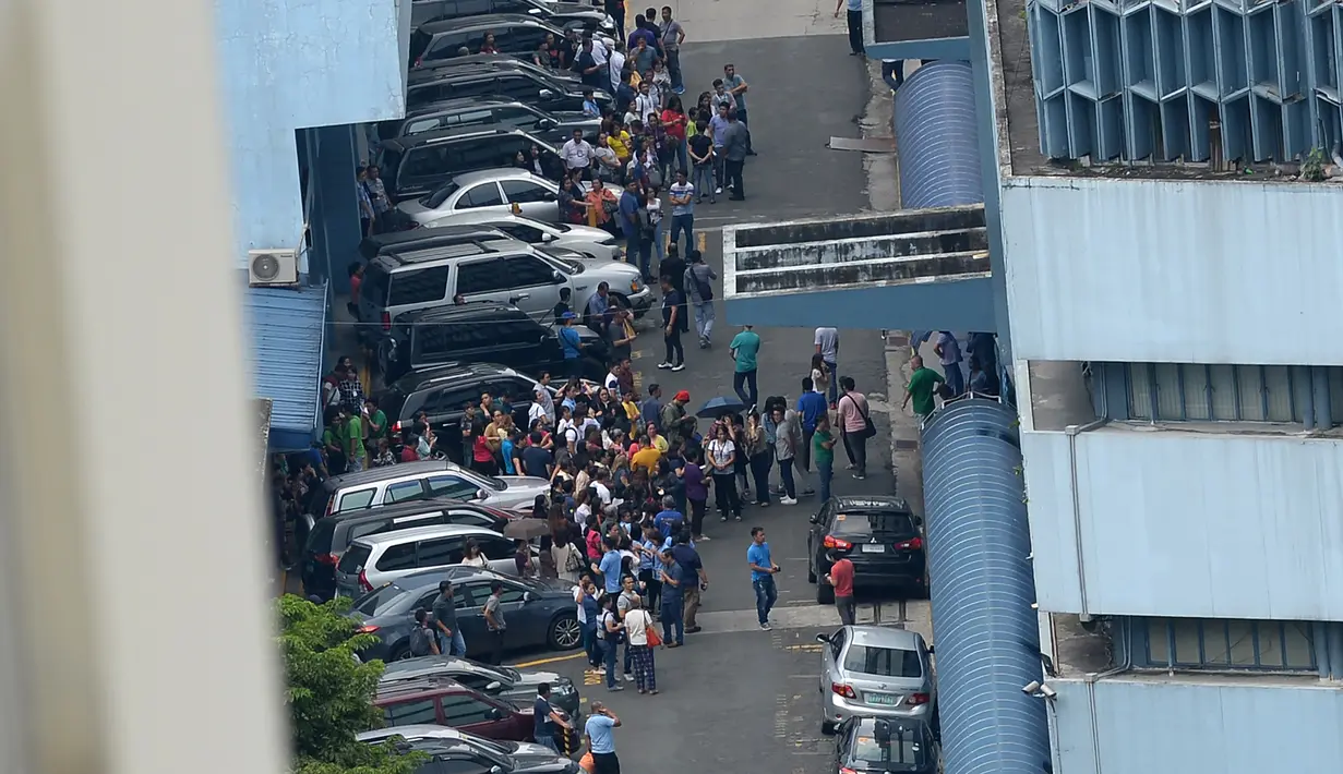 Pegawai pengadilan berkumpul di depan gedung setelah gempa melanda Manila, Filipina (11/8). Gempa berkekuatan 6,2 skala Ritcher itu terjadi pada pukul 13.30 waktu setempat. (AFP Photo/Ted Aljibe)