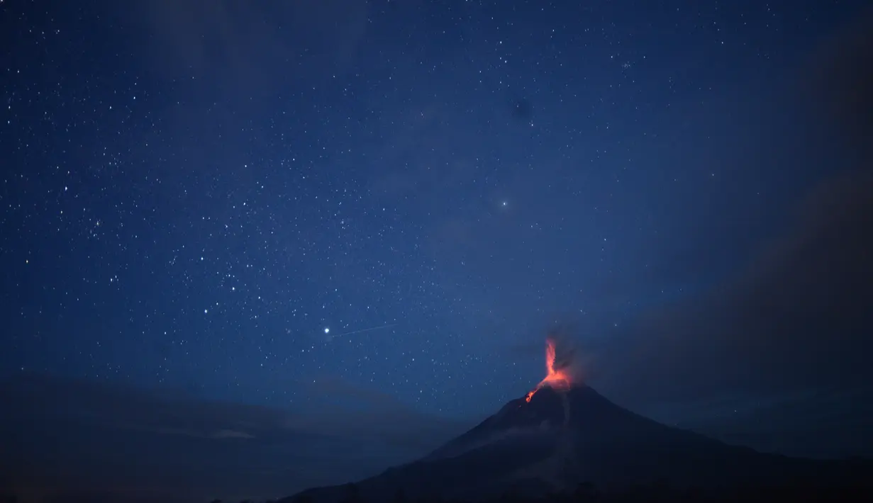 Foto yang diambil dengan exposure yang lama menunjukkan, cahaya bintang menerangi langit berpadu dengan Gunung Sinabung yang sedang memuntahkan lahar di Karo, Sumatera Utara (28/12). (AFP/Lana Priatna)
