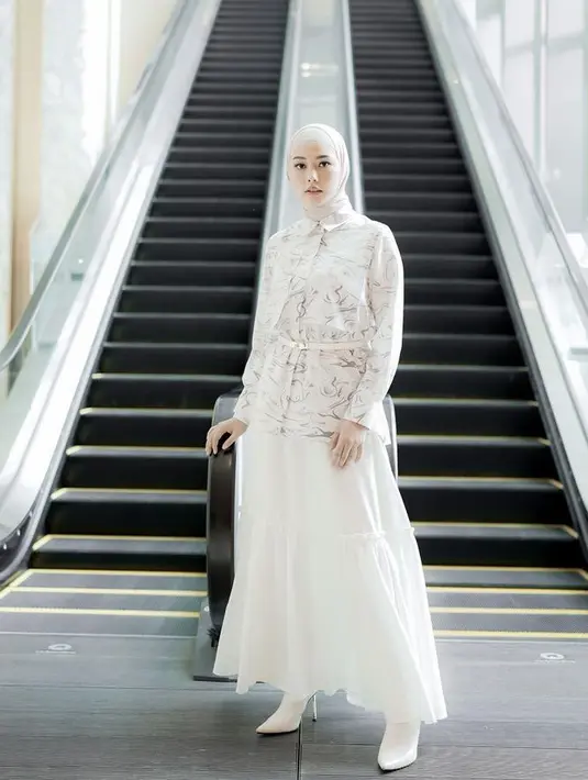 Tampil serba putih di hari raya dengan atasan kemeja lengan panjang berkotif dipadukan rok ruffle dan kerudung lilitnya.  [@daraarafah]