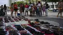 Orang-orang melihat sepatu dengan nama-nama perempuan korban femisida di Brasil dalam acara Hari Internasional untuk Penghapusan Kekerasan terhadap Perempuan di Pantai Copacabana, Rio de Janeiro, Sabtu (25/11/2023). (Tercio TEIXEIRA / AFP)