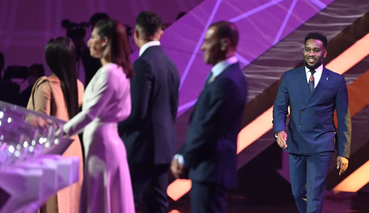 Mantan pesepak bola Nigeria Jay-Jay Okocha (kanan) tiba di atas panggung saat pengundian atau drawing Piala Dunia 2022 Qatar di Doha Exhibition and Convention Center pada 1 April 2022. (GABRIEL BOUYS / AFP)