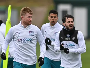 Gelandang Manchester City, Kevin De Bruyne (kiri) dan Bernardo Silva (kanan) berbincang selama sesi latihan di Manchester, Inggris (4/4/2022). Man City akan bertanding melawan Atletico Madrid pada leg pertama perempat final Liga Champions di Etihad Stadium. (AFP/Paul Ellis)