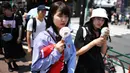 Dua orang wanita memegang kipas portabel saat mereka melintasi jalan selama gelombang panas di distrik Shin-Okubo Tokyo, Minggu (4/8/2019). Setelah menyerang beberapa wilayah di Eropa, suhu tinggi juga terjadi di Jepang. (Charly TRIBALLEAU / AFP)