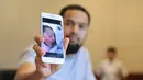 Wisnu menunjukkan foto melalui handphone yang dipegangnya. Foto anak ketiga perempuan yang diberi nama Cut Shafiyyah Mecca Alfatih. (Adrian Putra/Bintang.com)