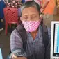 Seorang pedagang di Pasar Raya Padang sedang melakukan cek kesehatan d=sebelum divaksin. (Liputan6.com/ Novia Harlina)