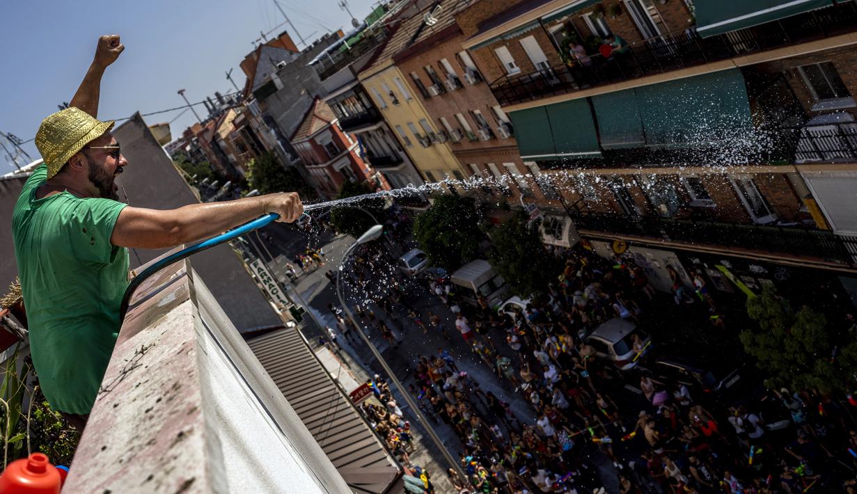 Seorang pria menyemprotkan air menggunakan selang saat perang air tahunan di jalan-jalan lingkungan Vallecas, Madrid, Spanyol, 17 Juli 2022. Selain warga sekitar, acara ini juga diikuti orang-orang dari daerah lain di Madrid bahkan turis asing. (AP Photo/Manu Fernandez)