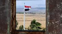 Bendera Suriah berkibar di Kota Quneitra menghadap sisi Dataran Tinggi Golan yang dianeksasi Israel. (AP/Louiai Beshara)