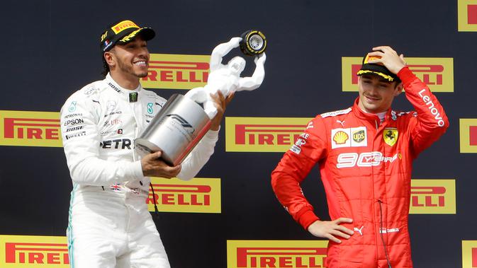 Pebalap Mercedes Lewis Hamilton (kiri) memegang trofi juara disaksikan pebalap Ferrari Charles Leclerc setelah menjuarai F1 GP Prancis 2019 di Sirkuit Paul Ricard, Minggu (23/6/2019). Hamilton tampil dominan dan menjadi juara F1 GP Prancis 2019. (AP Photo/Claude Paris)