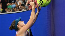 Petenis asal Swiss Belinda Bencic memberikan tanda tangan setelah kemenangannya melawan Viktoriya Tomova dari Bulgaria selama pertandingan tunggal putri mereka pada hari kedua Australia Terbuka di Melbourne, Selasa (17/1/2023). Selain bola-bola, foto dan halaman tertentu majalah tenis menjadi barang favorit yang disodorkan fans ke petenis favoritnya. (WILLIAM WEST / AFP)