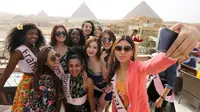 Para Kontestan Miss ECO Universe berselfie dengan latar belakang segitiga piramida di pinggiran Kairo, Mesir (10/4). Pemenang Miss Eco Universe 2016 akan memenangkan hadiah uang tunai USD 10.000. (REUTERS/Mohamed Abd El Ghany)