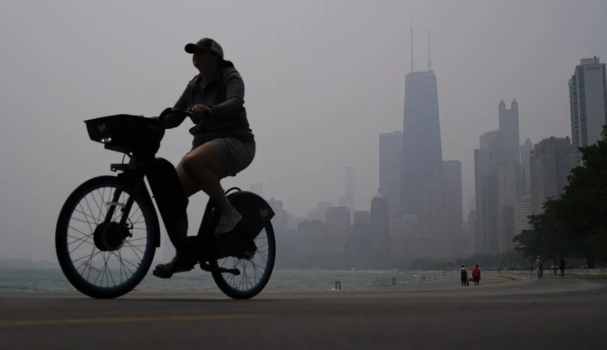 Seseorang mengendarai sepeda di sepanjang tepi Danau Michigan saat cakrawala pusat kota diselimuti kabut asap dari kebakaran hutan Kanada di Chicago, Selasa, 27 Juni 2023. (AP Photo/Kiichiro Sato)
