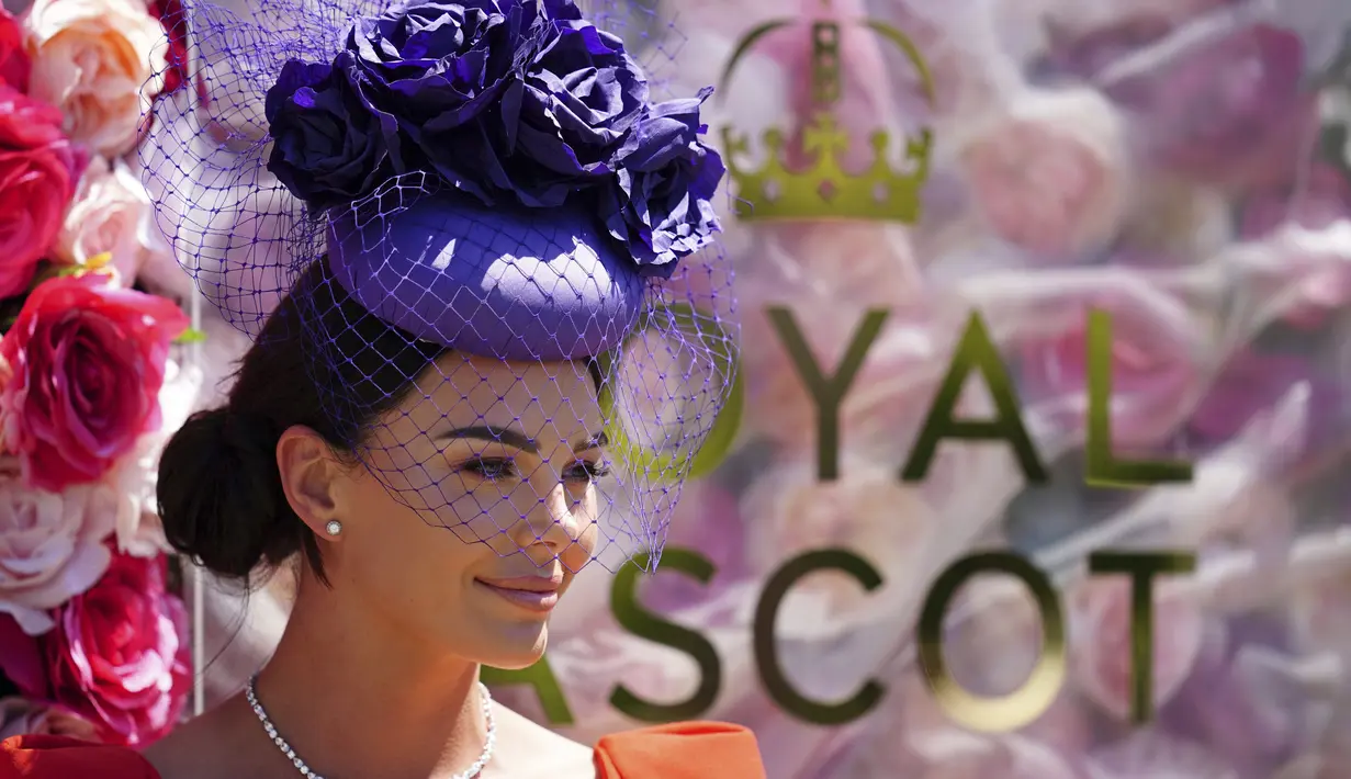 Seorang penonton wanita mengenakan topi bunga berpose untuk foto pada hari pertama acara balap kuda Royal Ascot, di Ascot Racecourse, di Ascot, Inggris, Selasa (14/6/2022). (AP Photo/Alastair Grant)