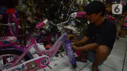 Aktivitas pekerja yang tengah merakit sepeda di toko sepeda Kramat Jati, Jakarta, Selasa (7/12/2021). Pandemi Covid-19 yang sedang terjadi membuat tren olahraga bersepeda semakin banyak diminati mulai dari anak-anak hingga orang dewasa dan lanjut usia. (merdeka.com/Imam Buhori)