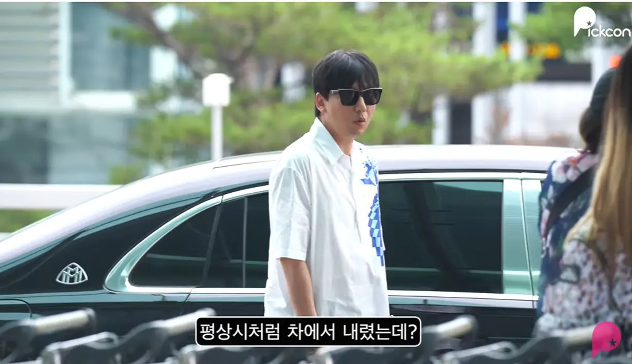 Kim Nam Gil mengenakan kemeja putih bercorak biru yang dipadukan dengan celana panjang hitam. Dia turun dari mobil dengan ekspresi terkejut.