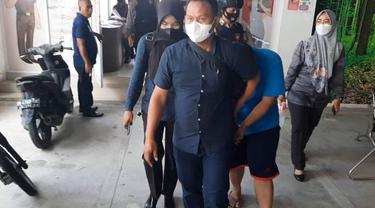 Anak sambung anggota DPRD Pekanbaru (baju biru) saat dibawa polisi dari Kejari Pekanbaru.