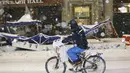 Seorang pria bersepeda melewati area makan luar ruangan yang roboh di sebuah restoran di New York, Amerika Serikat (16/12/2020). Badai salju menyebabkan akumulasi lebih dari 40 inci di beberapa tempat dan lapisan es yang licin. (Xinhua/Wang Ying)