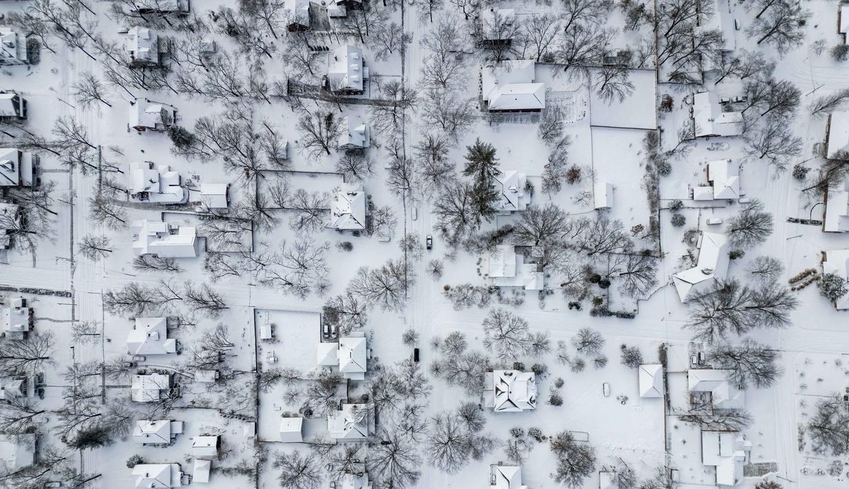 NWS juga memperingatkan munculnya kombinasi salju, hujan beku, dan angin kencang dapat memperburuk kondisi darurat, terutama di wilayah selatan yang jarang mengalami cuaca dingin ekstrem dan memiliki kesiapan infrastruktur terbatas. Tampak foto udara menunjukkan beberapa inci salju baru menutupi lingkungan perumahan pada Minggu 25 Januari 2026 di Columbia, Missouri. (Austin Johnson/AFP)
