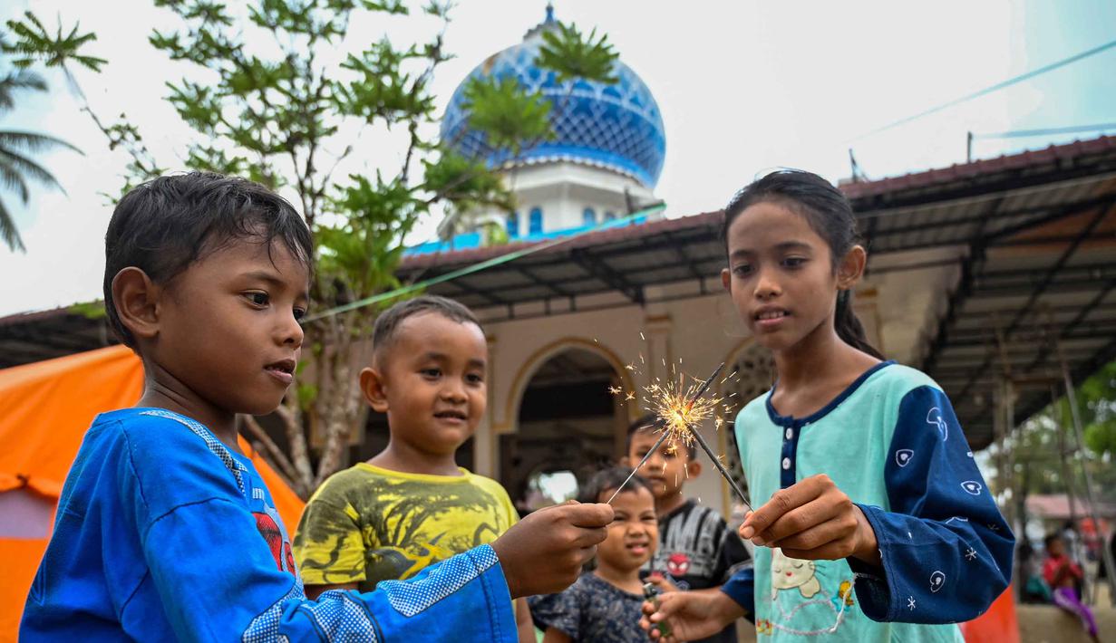 Anak-anak bermain kembang api di dekat tenda-tenda yang didirikan untuk para korban banjir di kompleks sebuah masjid, Meurah Dua, Kabupaten Pidie Jaya, Provinsi Aceh, pada 21 Februari 2026, setelah banjir dan tanah longsor dahsyat melanda Sumatra, akhir November 2025 lalu. Bulan Ramadan 1447 Hijriah atau 2026 Masehi dijalani dengan penuh keprihatinan oleh warga di Kabupaten Pidie Jaya, Provinsi Aceh. (CHAIDEER MAHYUDDIN/AFP)