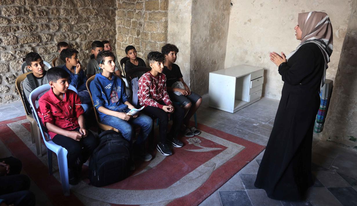 Anak-anak Palestina menghadiri kelas di sekolah bersejarah "Al-Kamaliya al-Othmanya" di Kota Tua Gaza yang menjadi bagian dari inisiatif sukarelawan yang diorganisir oleh para guru pengungsi, di Kota Gaza pada 2 November 2025. Diketahui, ada lebih dari 650 ribu anak kehilangan akses pendidikan formal sejak perang antara Israel dan Hamas memanas pada Oktober 2023. (Omar AL-QATTAA/AFP)