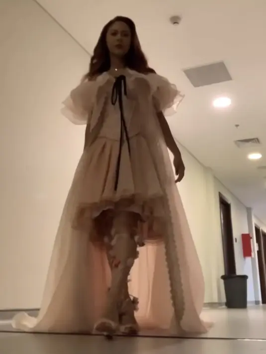Nadin Amizah mengenakan dress  model korset dengan rok pleated dan train warna pastel dengan detail pita hitam dari Wiranti Kurnia. Dipadukan stocking beraksen bunga dan heelsnya. [@cakecaine]