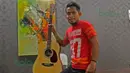 Andik Vermansah berpose dengan gitar miliknya dalam apartemen di kawasan Shah Alam, Selangor, Malaysia, Rabu (27/01/2016). (Bola.com/Nicklas Hanoatubun)