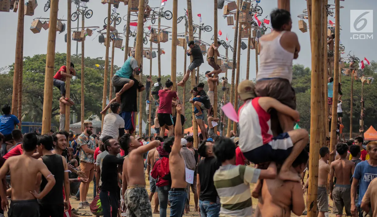 Warga mengikuti lomba Panjat Pinang Kolosal dalam rangka merayakan HUT ke-74 Kemerdekaan RI di Pantai Karnaval Ancol, Jakarta, Senin (17/8/2019). Sebanyak 174 batang pinang dengan beragam hadiah disediakan dalam lomba yang diikuti ratusan warga itu. (Liputan6.com/Faizal Fanani)