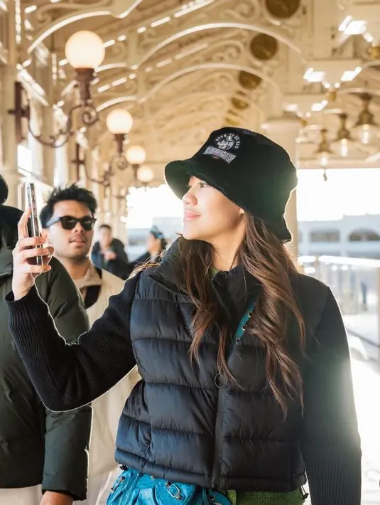 Penampilan tersebut dipadukan dengan knit short jacket hijau dari Uniqlo seharga Rp599 ribuan. Serta mengenakan bucket hat hitam dari Tokyo Disney seharga Rp922 ribuan. Ia juga membawa sling bag Balenciaga warna biru seharga Rp40 jutaan.  [@aaliyah.massaid]