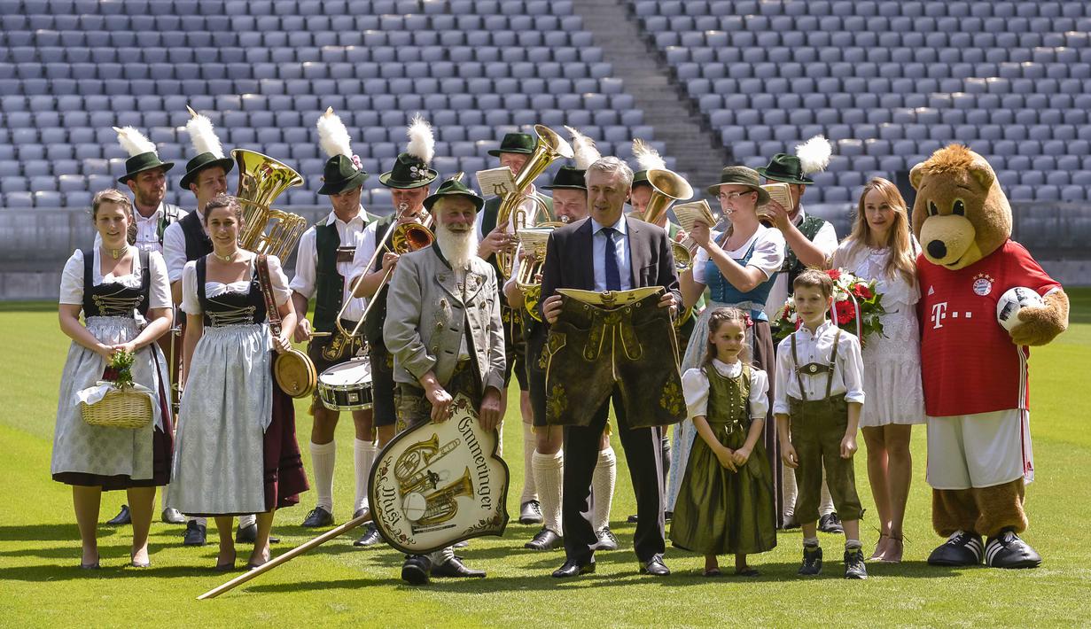 Pelatih anyar Bayern Munchen, Carlo Ancelotti saat foto bersama celana tradisional Bavaria dan tim musik yang berpakaian tradisional Bavaria di Stadion klub FC Bayern Munich, Jerman, (11//7/2016). (AFP/Guenter Schiffmann)