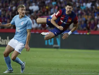Penyerang Barcelona Robert Lewandowski terbang di udara setelah melakukan kontak dengan bek Celta Vigo, Carl Starfelt pada pekan ke-6 Liga Spanyol 2023/2024 di Estadio Olimpic Lluis Companys, Minggu (24/9/2023) dini hari WIB. (AP Photo/Joan Monfort)