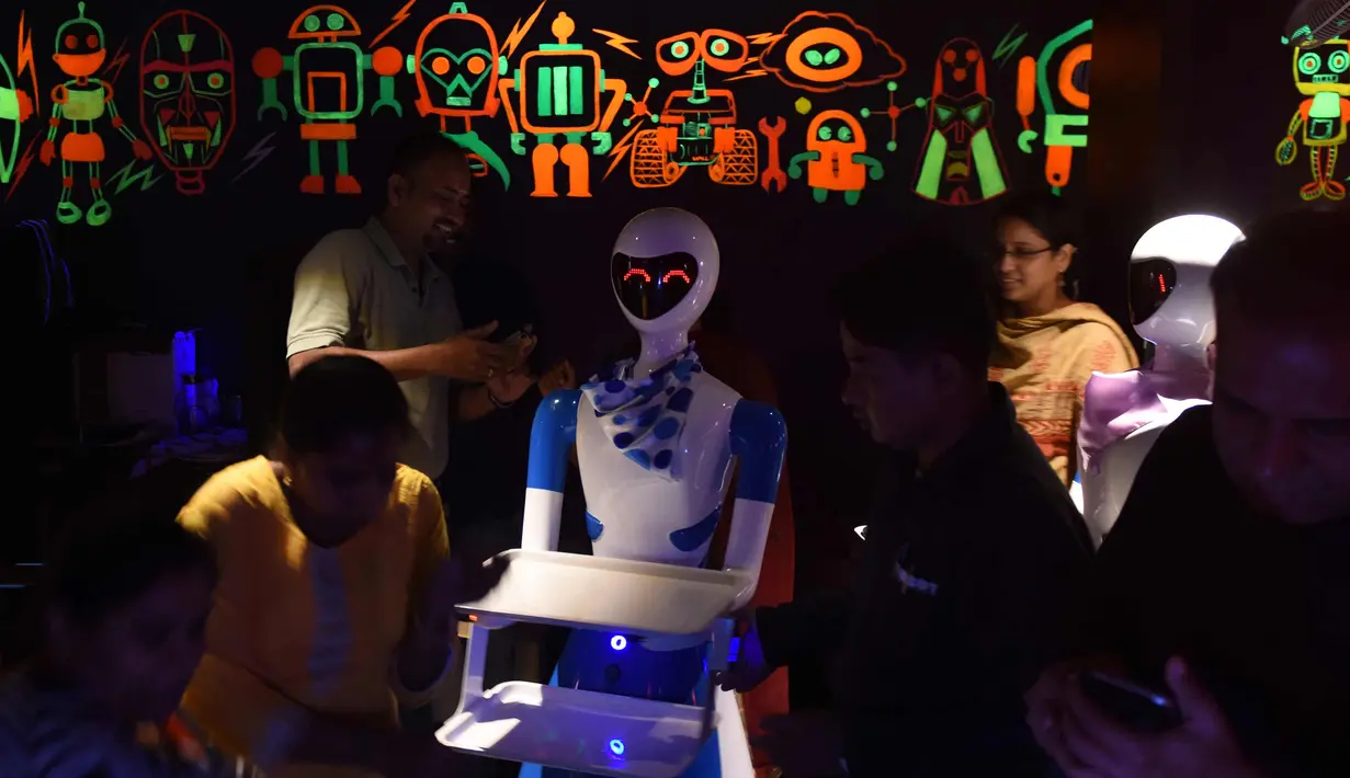 Pengunjung saat berada di restoran bertema robot di Chennai, India (20/12). Restoran ini merupakan yang pertama di India yang memiliki pelayan robot dengan server otomatis membawa piring dari dapur ke pelanggan. (AFP Photo/Arun Sankar)