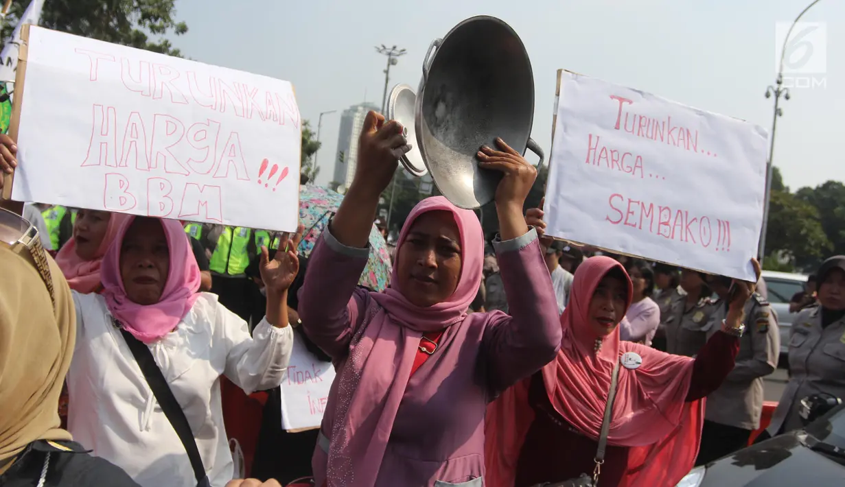 Seorang ibu dari Barisan Emak-Emak Militan Indonesia membawa wajan saat menggelar aksi di seberang Istana Merdeka, Jakarta, Rabu (18/7). Massa juga membawa berbagai tulisan berisi tuntutan untuk menurunkan harga bahan pokok. (Liputan6.com/Arya Manggala)
