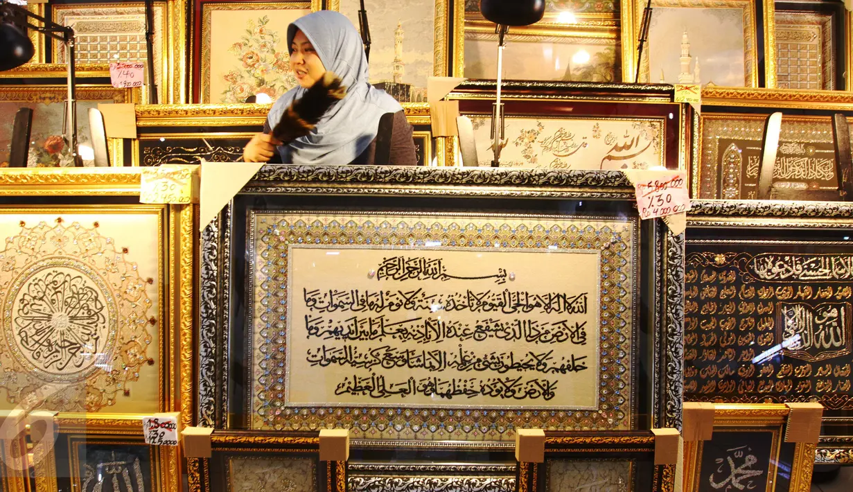 Pedagang tengah membersihkan kaligrafi di pusat perbelanjaan di Jakarta, Rabu (22/6). Kaligrafi dijual dengan kisaran harga jual ratusan hingga puluhan juta rupiah tergantung motif dan tingkat kesulitan pembuatan. (Liputan6.com/Angga Yuniar)