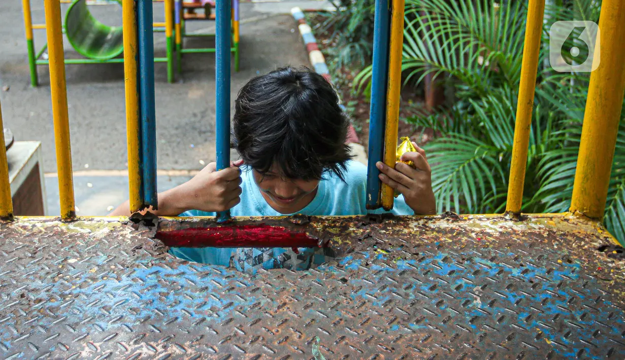 Seorang anak bermain dengan kondisi fasilitas yang rusak di Ruang Publik Terpadu Ramah Anak (RPTRA) Amir Hamzah, Jakarta, Rabu (12/7/2023). RPTRA Amir Hamzah terpantau tak terawat dengan wahana bermain yang rusak dan besi-besi berkarat. (Liputan6.com/Faizal Fanani)