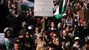 Hingga kini, serangan Israel di Gaza telah menewaskan lebih dari 72.000 warga Palestina dan melukai lebih dari 171.000 lainnya, serta menghancurkan sekitar 90 persen infrastruktur di wilayah tersebut. Tampak dalam foto, para pengunjuk rasa memegang bendera dan spanduk di luar stasiun Flinders Street selama kunjungan Presiden Israel, Isaac Herzog, di Melbourne, Australia, pada Kamis 12 Februari 2026. (MARTIN KEEP/AFP)