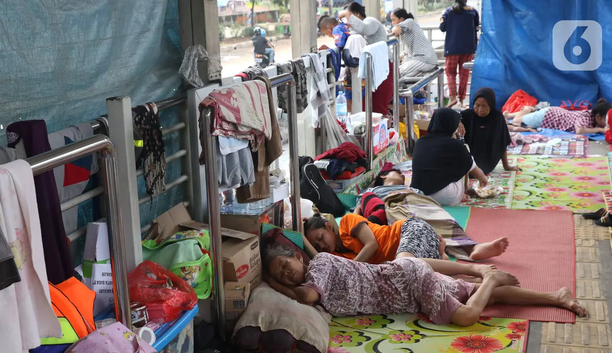 Warga korban banjir mengungsi di Halte Transjakarta Jembatan Baru, Cengkareng, Jakarta, Jumat (3/1/2020). Warga sekitar terpaksa mengungsi ke Halte Transjakarta Jembatan Baru karena rumah mereka masih terendam banjir. (Liputan6.com/Angga Yuniar)