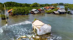 Ancaman tenggelamnya wilayah pesisir utara Jawa Tengah disebabkan oleh dua faktor utama, penurunan muka tanah (land subsidence) akibat penyedotan air tanah berlebihan serta kenaikan permukaan air laut yang diperparah oleh perubahan iklim global. Tampak dalam foto yang diambil pada 29 Juli 2025 menunjukkan pemandangan udara rumah-rumah yang terbengkalai dan sebagian terendam air, yang hilang akibat kenaikan pasang surut akibat perubahan iklim, di Desa Semonet, Pekalongan, Jawa Tengah. (BAY ISMOYO/AFP)