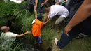 Petugas membantu tersangka pada rekonstruksi pencurian kabel gorong-gorong di Jalan Medan Merdeka Selatan, Jakarta, Selasa (15/3). Tersangka memperagakan cara masuk ke dalam lubang gorong-gorong dan cara mencuri kabel. (Liputan6.com/Immanuel Antonius)