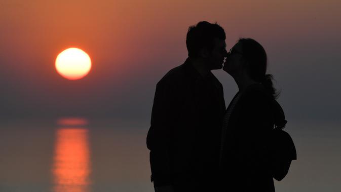 Pasangan berciuman saat matahari terbenam di Cap Frehel, di Plevenon, Prancis barat (26/2). Cap Frehel terletak 8,5 km dari pusat kota Fréhel, meskipun, secara administratif, terletak di dalam wilayah komune Plévenon. (AFP Photo/Loic Venance)