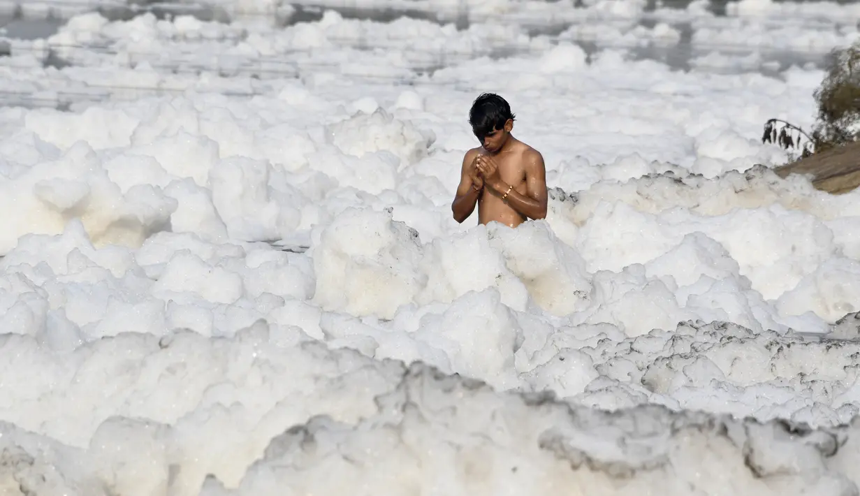 Seorang pria berdoa di Sungai Yamuna yang tercemar di New Delhi, Sabtu (8/7). Umat Hindu India mensucikan dua sungai di India yaitu Sungai Ganggga dan Yamuna. (DOMINIQUE FAGET / AFP)