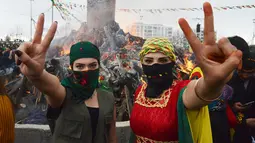 Dua wanita Kurdi Turki menunjukkan simbol perdamaian selama Perayaan Newroz di Diyarbakir, Turki (21/3). Festival ini untuk memperingati hari pertama musim semi, yang jatuh setiap tanggal 21 Maret. (AFP Photo / Ilyas Akengin)