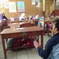 Nampak para siswa tengah berlindung dibawah meja saat simulasi mitigasi bencana diajarkan para mahasiswa (Liputan6.com/Jayadi Supriadin)