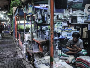 Pedagang bermain samrtphone saat menunggu pembeli di kios Pasar Ikan Hias Sumenep, Jakarta, Minggu (14/11/2021).  KKP meminta para pedagang hewan peliharaan yang selama ini berjualan di sosial media seperti Facebok dan Instagram untuk beralih ke platform lain. (merdeka.com/Iqbal S. Nugroho)