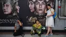 Seorang wanita menghitung uang di depan poster film Asura di stasiun kereta bawah tanah Beijing, Selasa (17/7). Para produsen berencana mengolah kembali film itu dan merilisnya lagi di kemudian hari untuk mengurangi kerugian 700juta Yuan. (AFP/GREG BAKER)