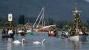Warga Desa Moos memasuki Pelabuhan Radolfzell sambil manaiki kapal berhias bunga saat mengikuti Pawai Air Mooser di Danau Constance, Jerman, Senin (22/7/2019). Pawai Air Mooser digelar setiap tahun pada Senin ketiga di bulan Juli. (Patrick Seeger/DPA/AFP)
