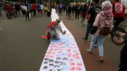 Warga berpose di dekat spanduk sepanjang satu kilometer bekas Cap tangan anak-anak Indonesia, di Kawasan Car Free Day, Jakarta (24/9). Spanduk tersebut untuk menunjukkan dukungan kepada Etnis minoritas Rohingya di Myanmar. (Liputan6.com/Johan Tallo)