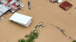 Topan Super Fung-wong merupakan badai tropis ke-21 yang melanda Filipina tahun ini. Tampak foto udara menunjukkan seorang warga mengayuh perahunya di air banjir yang melanda rumah-rumah terendam di Kota Tuguegarao, Provinsi Cagayan, di utara Manila pada 10 November 2025, setelah sungai meluap akibat hujan deras yang disebabkan oleh Topan Super Fung-wong. (John DIMAIN/AFP)