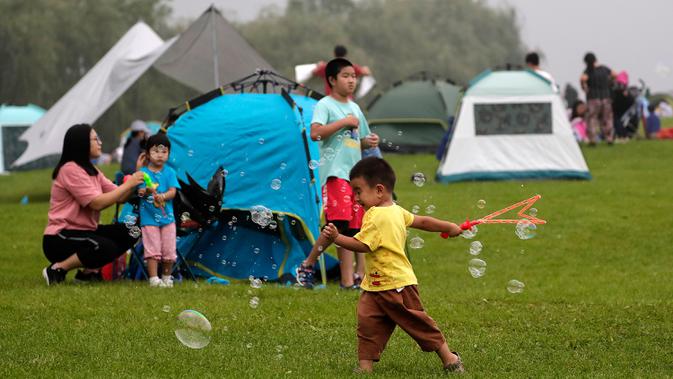Seorang anak bermain gelembung saat orang-orang berkemah di gunung yang indah di Yanqing, Beijing pada 30 Agustus 2020. China memiliki lebih dari 200 orang yang dirawat di RS karena COVID-19, dengan lebih dari 300 lainnya diisolasi setelah dites positif terkena virus tanpa gejala. (AP/Andy Wong)