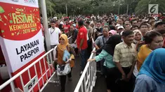 Petugas mengatur warga yang mengantre untuk membuat paspor dalam acara Festival Keimigrasian 2018 di Lapangan Barat Daya Monas, Jakarta, Minggu (21/1). Para pembuat paspor mengantre sejak pagi. (Liputan6.com/Arya Manggala)