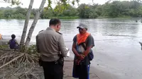 Seorang petugas kepolisian tengah melakukan identifikasi korban yang hilang di muara Sungai Cibaluk, Garut (Liputan6.com/Jayadi Supriadin)